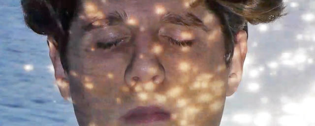 jay plus dressed in black pants and an OSHA orange jacket and beanie. the jacket has silver reflective stripes on it. they're walking purposefully toward a large pile of orange and white road construction barrels.