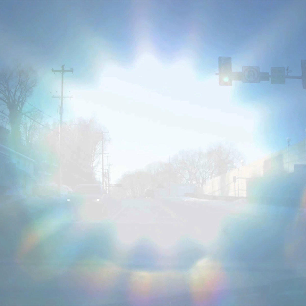 a double exposure of a suburban intersection and a close-up of the sun in the sky.